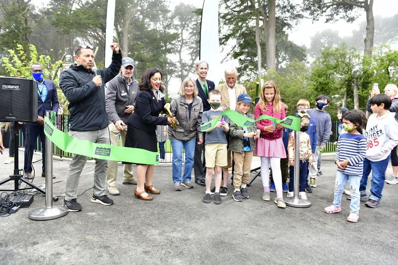 Ribbon cutting ceremony showing multiple people behind a green ribbon