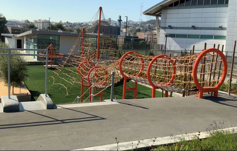 Margaret Hayward Orange net and tube structure Playground and glass Building