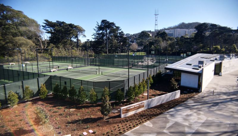 View from the back of the tennis center clubhouse. Planter bed in front of two of the courts. Opens in new window