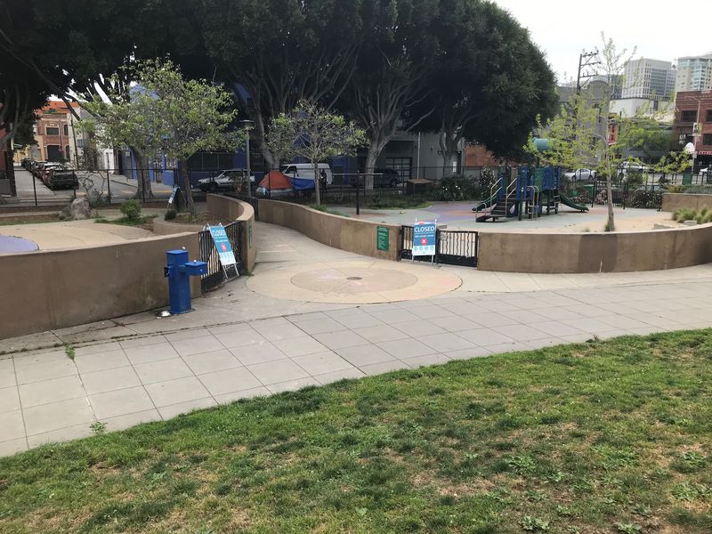 Walkway between the play areas, which are surrounded by a cement wall and COVID safety signs
