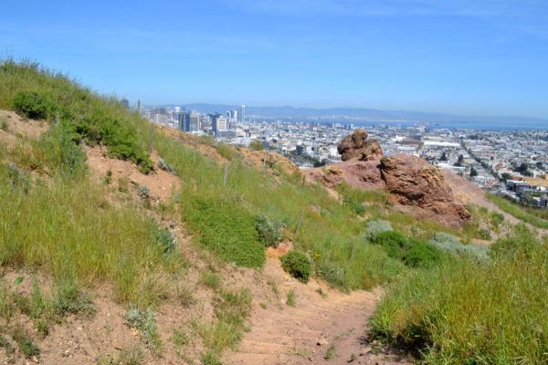 Dirt trail leading down a hill toward the city